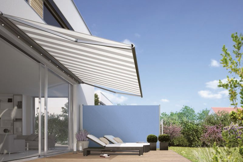 Sonnenschutz in Form einer Markise über einer Terrassensituation mit Liegen und grüner Umgebung. Sonnenschutz in Form einer Markise über einer Terrassensituation mit Liegen und grüner Umgebung.