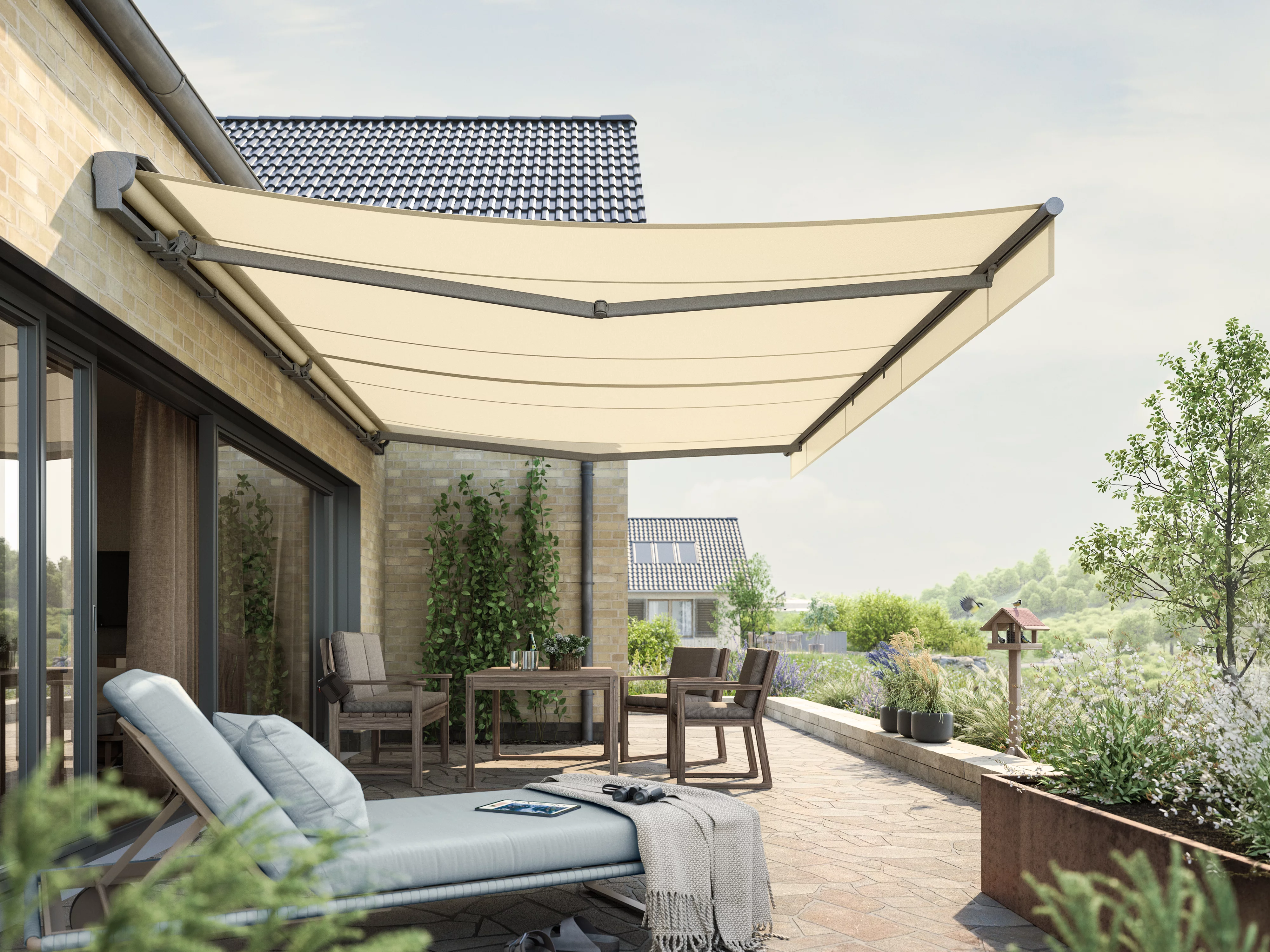 Markise in hellem Beige über einer Terrassensituation mit Sitzgelegenheiten und Pflanzen im Hintergrund.