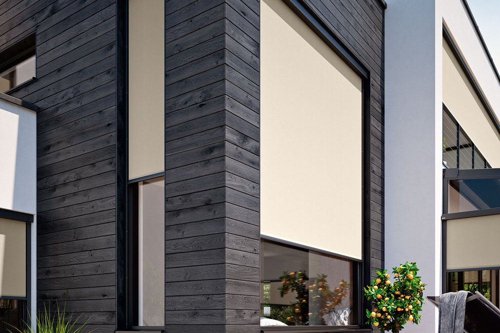 Moderne Hausfassade mit Markisen in hellen Farben und klaren Linien, umgeben von einer minimalistischen Terrassensituation.
