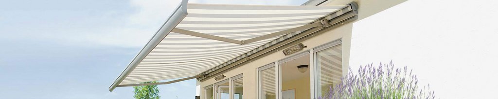 Markise mit gestreiftem Markisentuch über einer Terrassensituation, im Hintergrund ein heller Hausanbau. Markise mit gestreiftem Markisentuch über einer Terrassensituation, im Hintergrund ein heller Hausanbau.